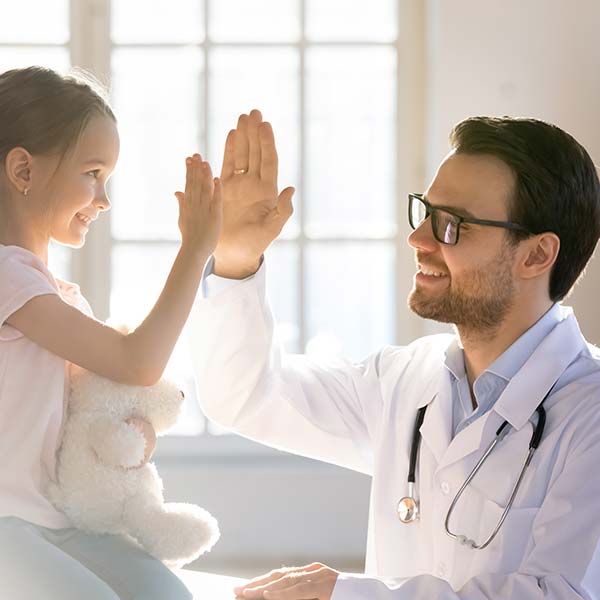 Happy little girl giving high-five to doctor